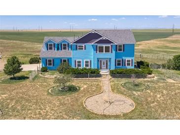 Two-story light blue house with landscaping and a long driveway at 8441 Flint Ridge St, Bennett, CO 80102