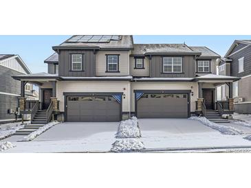 Two-story townhome showcasing attached garages, dark trim, and solar panels at 537 Nightsky St, Erie, CO 80516