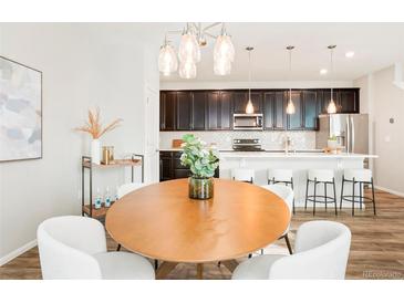 Modern kitchen featuring dark cabinets, stainless steel appliances, and a white countertop island with seating at 6041 N Orleans St, Aurora, CO 80019