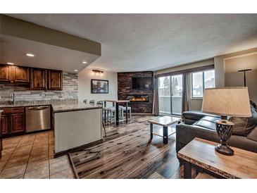 Cozy living room features a fireplace, tv, hardwood floors, and a sliding door to the balcony at 611 Village Rd # 620, Breckenridge, CO 80424