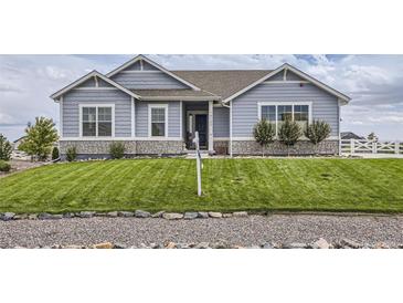 Ranch style home with gray siding, stone accents, and a landscaped lawn at 16122 Emporia Way, Brighton, CO 80602