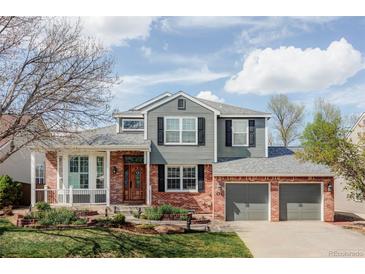 Charming two-story home featuring a manicured lawn, brick accents, and an attached two-car garage at 674 Huntington Dr, Highlands Ranch, CO 80126