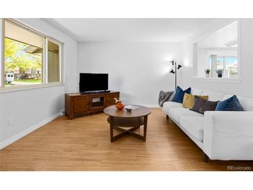 Inviting living room with hardwood floors, modern TV, white couch, and decorative pillows, perfect for relaxation at 4779 S Owens Way, Littleton, CO 80127