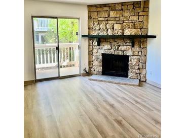 Spacious living room with a stone fireplace and sliding glass doors to a balcony at 4400 S Quebec St # 102R, Denver, CO 80237