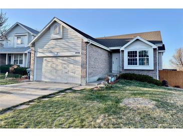 Charming home featuring a manicured front yard, attached garage, and stylish brick and siding exterior at 4036 S Himalaya Cir, Aurora, CO 80013