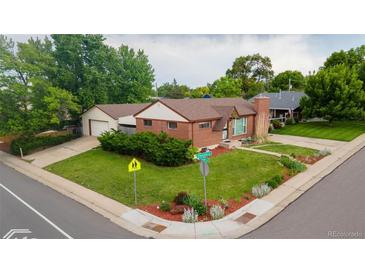 Charming brick home featuring a well-maintained lawn, mature trees, and a detached two-car garage at 920 Emerson Cir, Northglenn, CO 80233