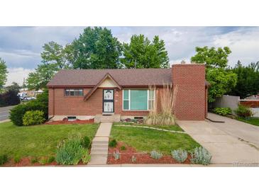 Charming brick home featuring a manicured lawn, complemented by mature trees, and a cozy front entrance at 920 Emerson Cir, Northglenn, CO 80233