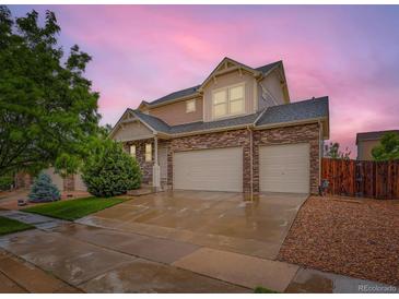 Beautiful two-story home with a three-car garage and stone accents under a lovely pink sky at 10570 Worchester Dr, Commerce City, CO 80022
