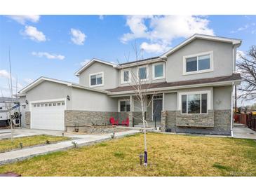 Inviting two-story home featuring a manicured lawn, stone accents, and an attached two-car garage at 3165 W 63Rd Ave, Denver, CO 80221