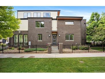 Contemporary brown brick home with a black fence, manicured lawn and garden at 3690 W Byron Pl, Denver, CO 80211