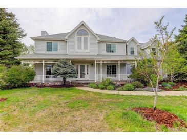 Inviting two-story home with a charming front porch, mature trees, and a well-manicured lawn at 31 N Algonquian St, Aurora, CO 80018