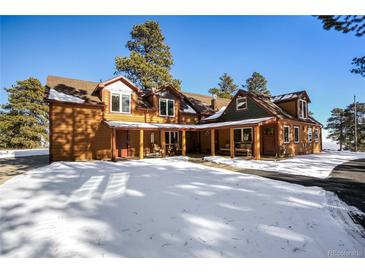 Mountain home exterior; log siding, multiple dormers, covered porch at 21531 Main Ave, Golden, CO 80401