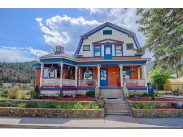 Charming home featuring a colorful exterior, inviting front porch, and landscaped garden at 209 10Th Ave, Idaho Springs, CO 80452