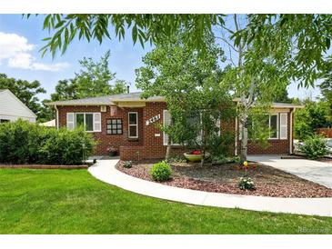 Charming brick home featuring a well-manicured lawn, garden beds and a welcoming walkway at 2461 Niagara St, Denver, CO 80207