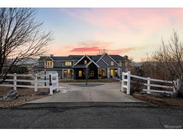 Stunning two-story home with a large driveway and white fence, beautiful sunset in the background at 7401 Deerfield Rd, Longmont, CO 80503