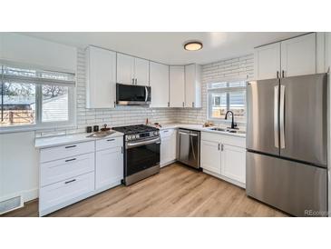 Modern kitchen featuring white cabinets, stainless steel appliances, and a subway tile backsplash at 1649 Lima St, Aurora, CO 80010