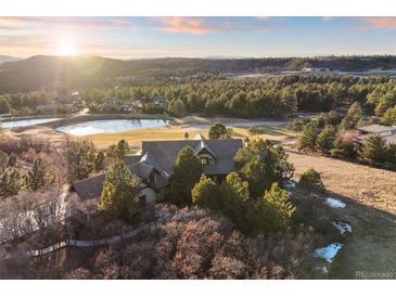 Stunning aerial view of a luxurious home surrounded by lush greenery and a serene pond, offering a picturesque setting at 1052 Country Club Estates Dr, Castle Rock, CO 80108