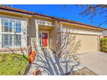 Charming home featuring a red front door, brick accents, and attached garage, creating a welcoming curb appeal at 16773 W 61St Ln, Arvada, CO 80403