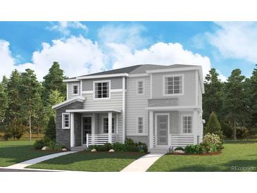 Charming two-story home showcasing a blend of stone and siding accents, complemented by a well-manicured lawn and mature trees at 1366 Penner Dr, Erie, CO 80026