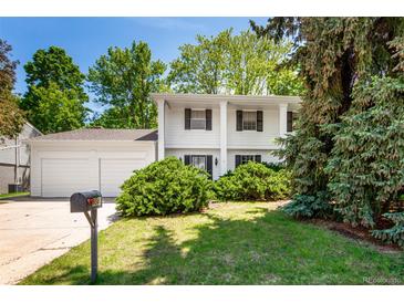 Charming two-story home with white exterior, well-manicured lawn, mature trees, and inviting curb appeal at 9540 E Grand Pl, Greenwood Village, CO 80111