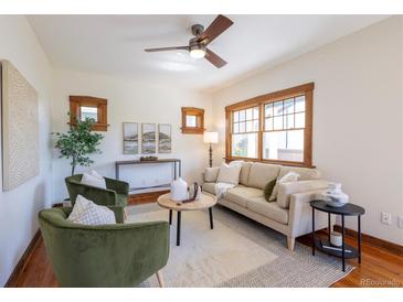 Bright living room features a ceiling fan, two arm chairs, and a cream colored couch at 1836 S Grant St, Denver, CO 80210
