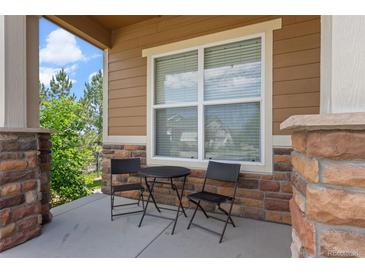 Inviting front porch with stone accents, outdoor seating, and views of the surrounding landscape at 15414 Xenia Ct, Thornton, CO 80602
