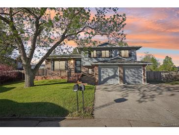 Charming two-story home with a lush front yard and a two-car garage at sunset at 4933 S Xenon Ct, Morrison, CO 80465