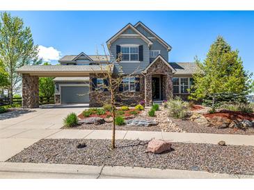 Charming two-story home with stone accents, a covered entrance, professional landscaping, and an attached two-car garage at 11857 S Saunter Ln, Parker, CO 80138