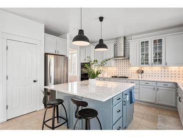 Well-lit kitchen featuring stainless steel appliances, white cabinets, and blue island with bar seating at 25362 E Indore Dr, Aurora, CO 80016