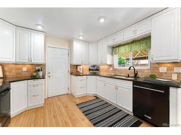 Traditional kitchen with white cabinetry, black countertops, and stainless steel appliances at 8475 W 74Th Dr, Arvada, CO 80005