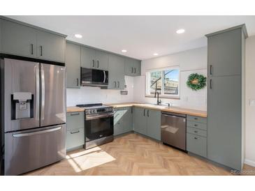 Updated kitchen features gray cabinets, butcher block counters, and stainless steel appliances at 9272 E Mansfield Ave, Denver, CO 80237