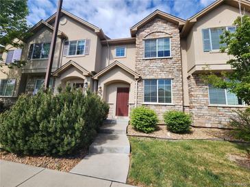 Charming townhome with stone accents, a manicured lawn, and a welcoming front entrance at 12753 Ivanhoe St, Thornton, CO 80602