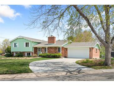 Charming home with a brick chimney, attached garage, well-maintained lawn, and a curving driveway at 588 Newark St, Aurora, CO 80010