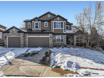 Two-story home with a brick and siding exterior, two car garage, and a snow covered front yard at 11701 Bent Oaks St, Parker, CO 80138