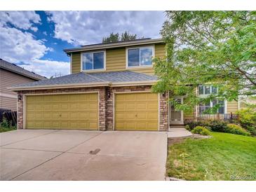 Charming two-story home featuring a three-car garage with stone accents, plus manicured lawn and mature landscaping at 7627 Halleys Dr, Littleton, CO 80125