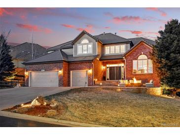 Beautiful brick home with a manicured lawn, three-car garage and charming front patio seating area at 6577 Esperanza Dr, Castle Pines, CO 80108