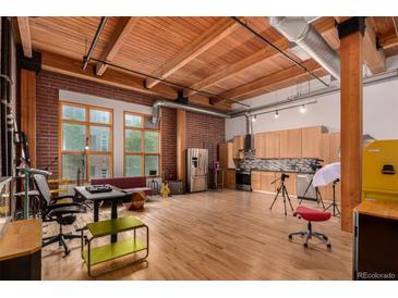 Spacious living room featuring exposed brick walls, wood ceilings, and modern kitchen amenities at 2955 Inca St # 2Q, Denver, CO 80202