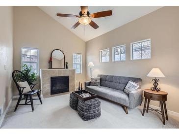 Bright living room boasts a fireplace, vaulted ceiling, neutral tones and a ceiling fan at 10148 E 29Th Dr, Denver, CO 80238