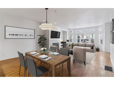 Open concept living room featuring a dining area and a sitting area with a fireplace and large windows at 30 Garfield St # G, Denver, CO 80206