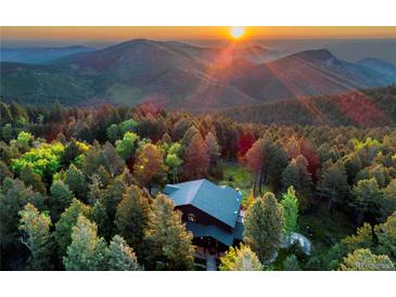 Stunning aerial view of mountain home surrounded by lush forest at sunset, offering seclusion and scenic beauty at 13416 Kuehster Rd, Littleton, CO 80127