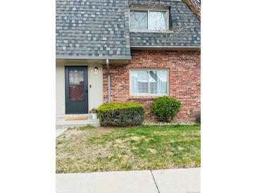 Charming townhouse exterior features a well-maintained lawn, bushes, and a welcoming front door at 15107 E Wesley Ave, Aurora, CO 80014