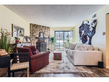 Cozy living room features a stone fireplace and access to a patio at 3576 S Depew St # 104, Lakewood, CO 80235