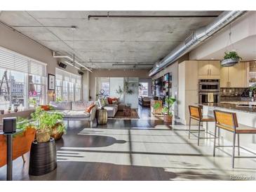 Spacious living room featuring hardwood floors, exposed ductwork, and large windows for lots of natural light at 1499 Blake St # 6K, Denver, CO 80202