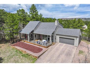 Charming gray home boasts a well-maintained lawn, cozy deck, and attached two-car garage at 3640 Summertime Ct, Monument, CO 80132