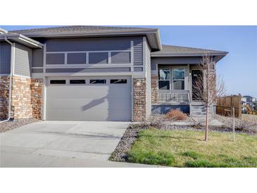 Inviting two-story home featuring stone accents, a gray facade, attached two car garage, and a well-manicured lawn at 3961 Happy Hollow Dr, Castle Rock, CO 80104