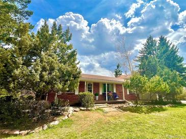 Charming brick home featuring a well-maintained front yard, mature trees, and inviting front porch with seating at 25 High St, Palmer Lake, CO 80133