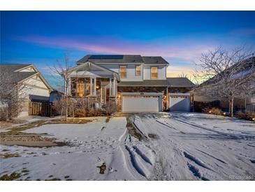 Charming two-story home featuring a three-car garage, stone accents, and a welcoming front porch at dusk at 226 N Millbrook St, Aurora, CO 80018