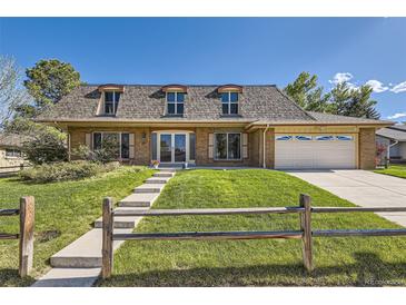 Charming brick home with a well-maintained front yard, lovely landscaping, and a classic design under a clear blue sky at 6708 W Portland Ave, Littleton, CO 80128