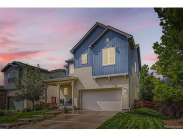 Two-story blue home featuring a two-car garage, covered porch, and manicured lawn at 859 Equinox Dr, Erie, CO 80516