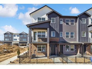 New townhome with modern design, balcony, brick accents, dark gray siding, and landscaped front yard at 6840 Merseyside Ln, Castle Pines, CO 80108